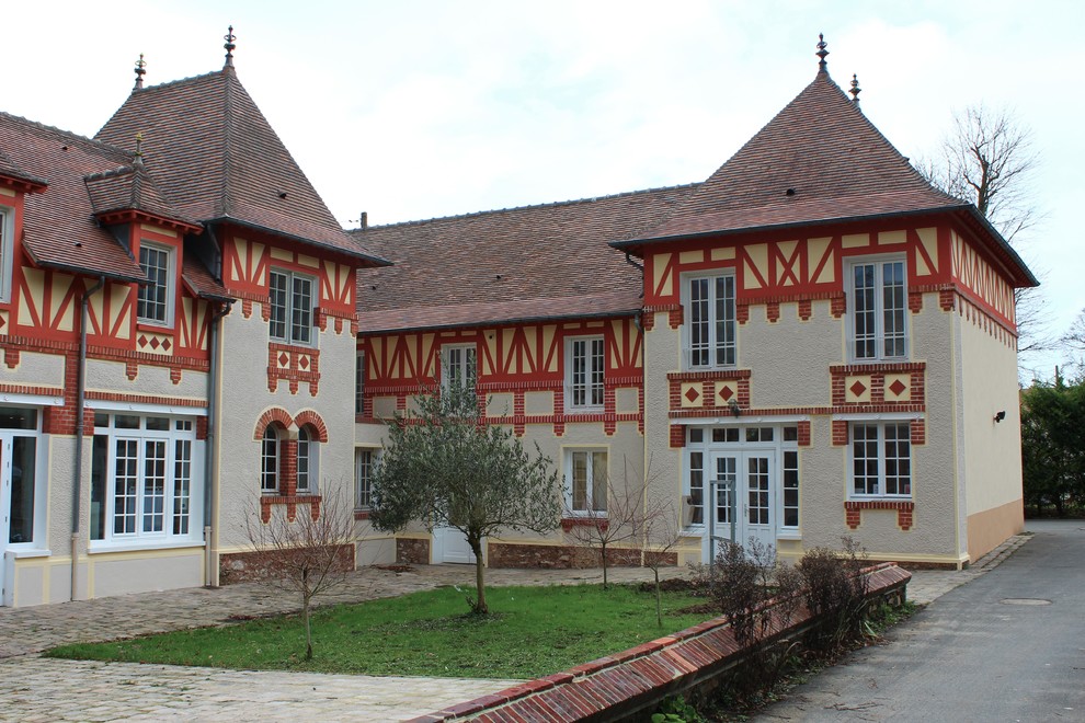 Cette image montre un grande façade d'immeuble traditionnel avec un revêtement mixte, un toit à quatre pans et un toit en tuile.