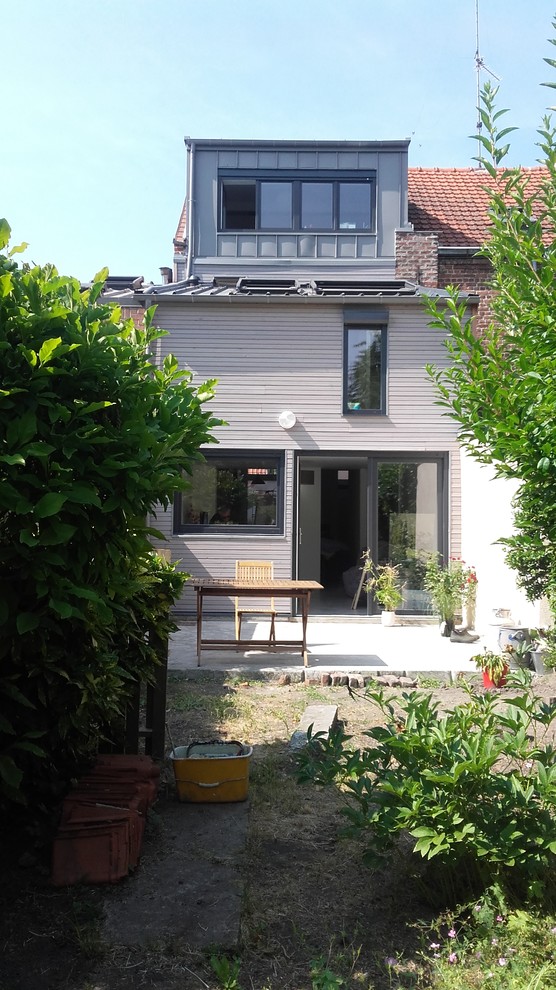This is an example of a contemporary house exterior in Lille with wood cladding, a lean-to roof and a mixed material roof.