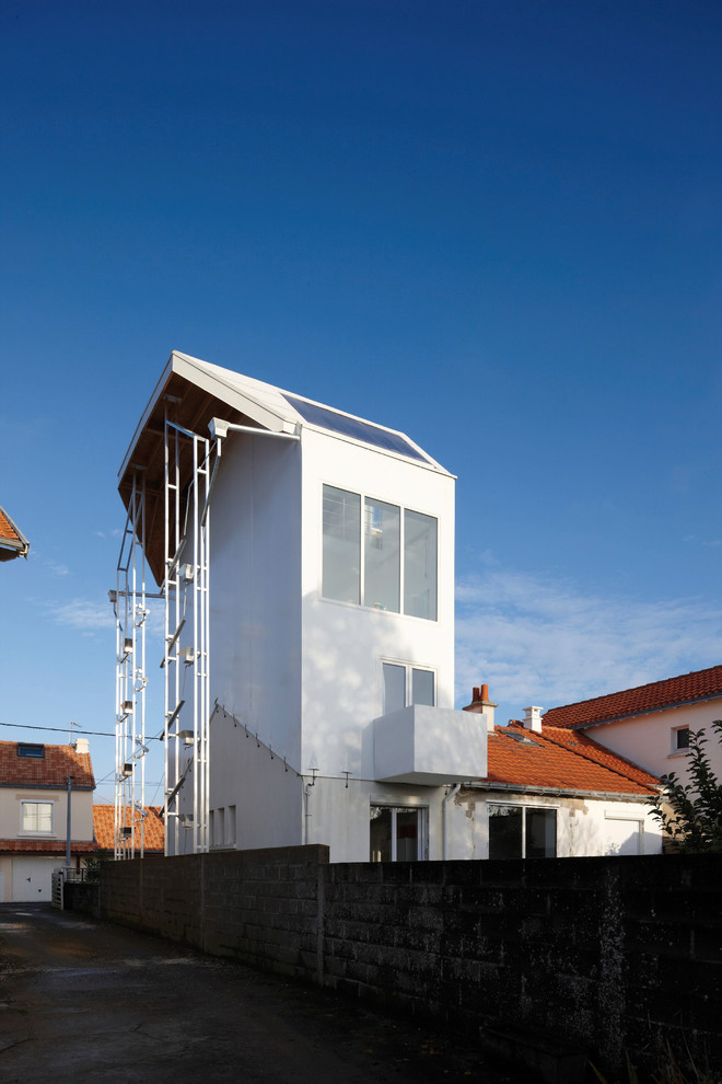 Cette image montre une façade de maison blanche design à deux étages et plus avec un toit à deux pans.