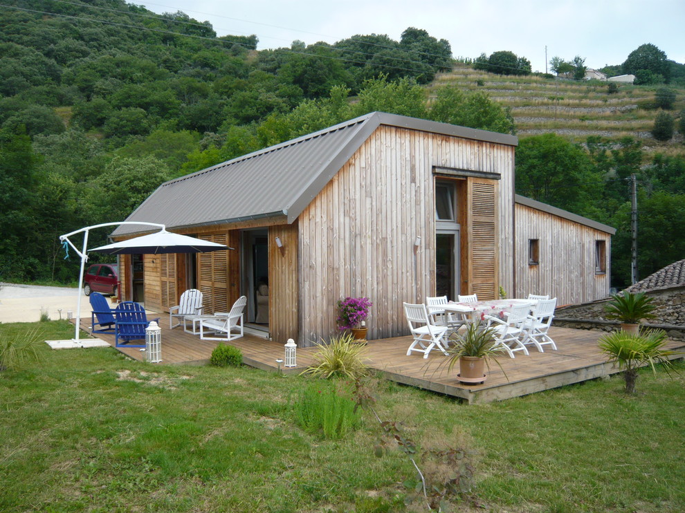 This is an example of a small contemporary bungalow detached house in Lyon with wood cladding and a metal roof.