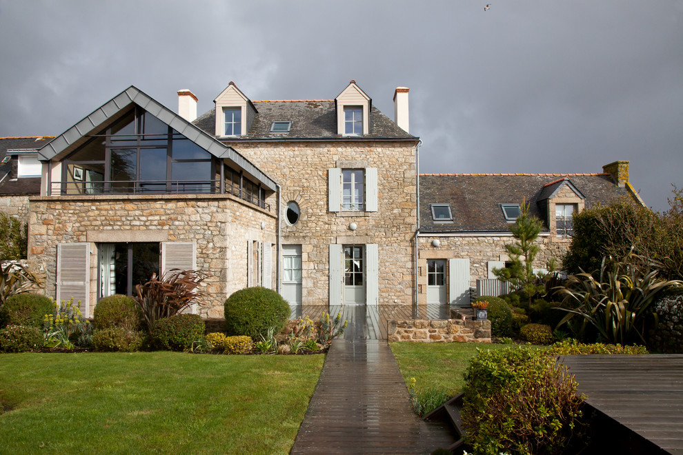 Cette photo montre une façade de maison beige chic en pierre de taille moyenne et à deux étages et plus avec un toit à deux pans.