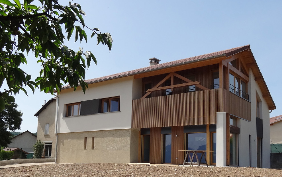 Cette photo montre une grande façade de maison beige tendance à un étage avec un revêtement mixte et un toit à deux pans.