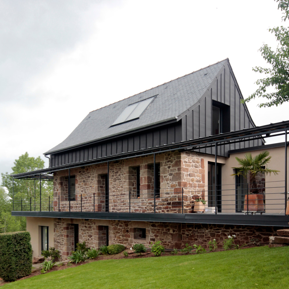 Diseño de fachada de casa gris contemporánea de tamaño medio de dos plantas con revestimiento de piedra, tejado a dos aguas y tejado de metal