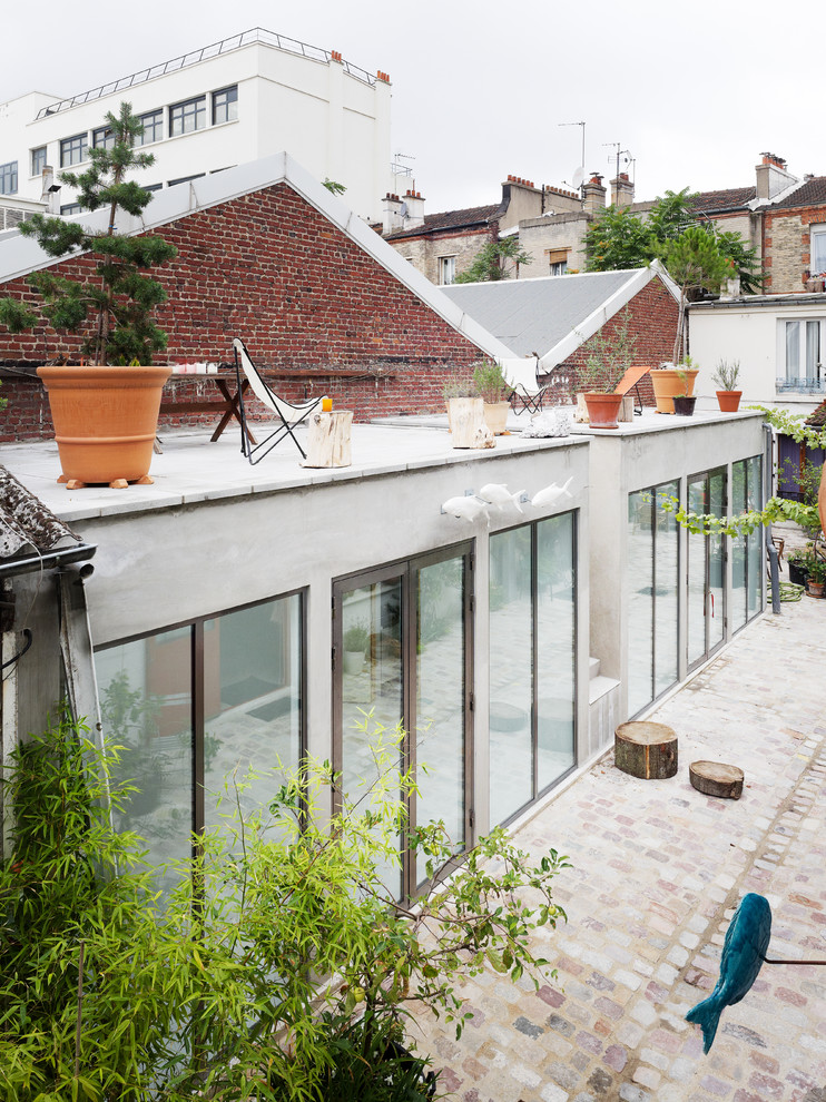 Photo of a medium sized and gey urban two floor brick house exterior in Paris with a flat roof.