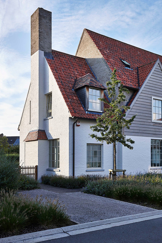 Foto de fachada blanca de estilo de casa de campo grande de dos plantas con revestimiento de ladrillo y tejado a dos aguas
