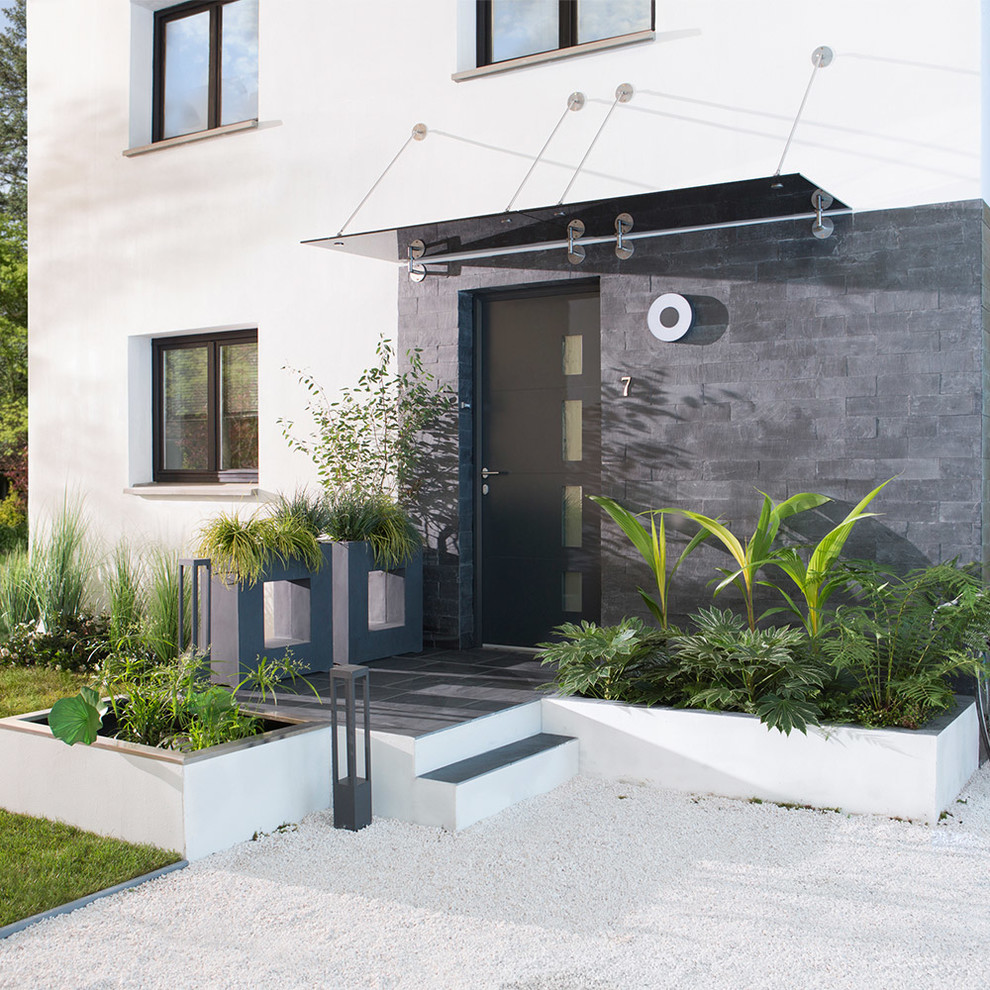Inspiration for a medium sized and white contemporary two floor house exterior in Lille with stone cladding and a flat roof.