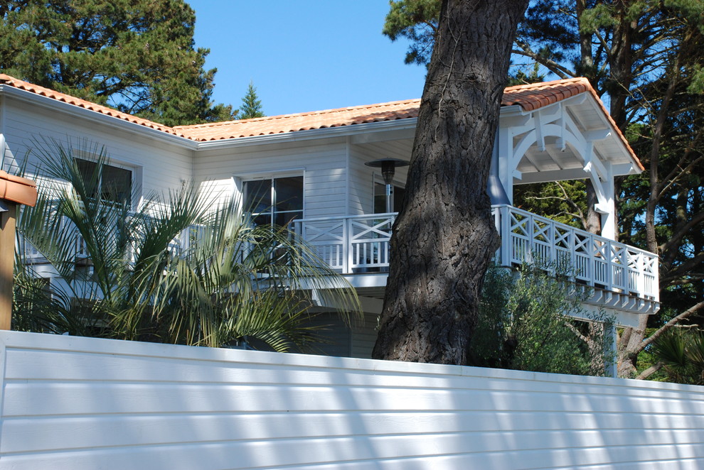 Cette image montre une façade de maison blanche traditionnelle en bois avec un toit à quatre pans.