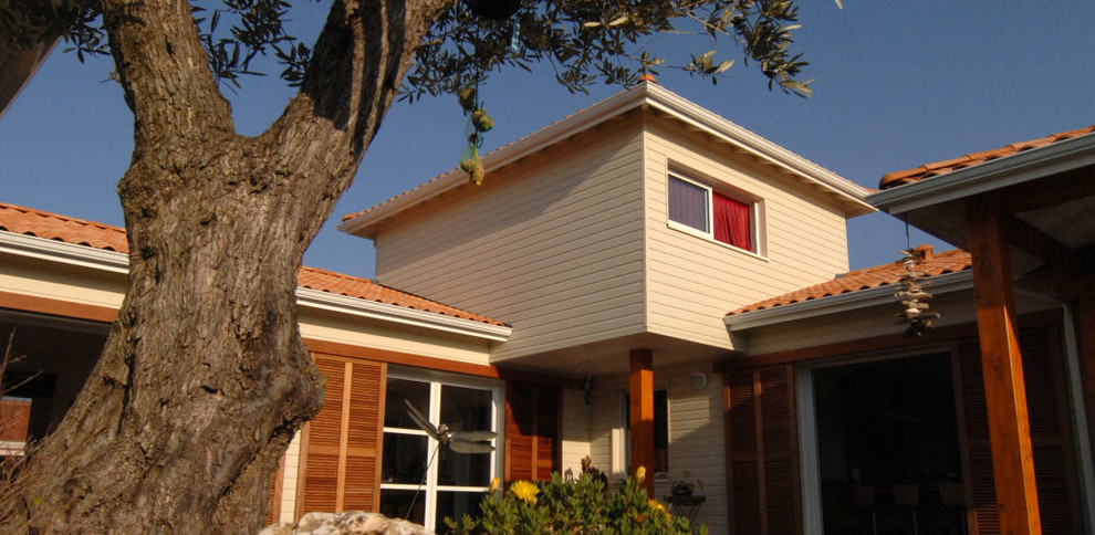 Idée de décoration pour une façade de maison beige marine à un étage avec un toit à quatre pans.
