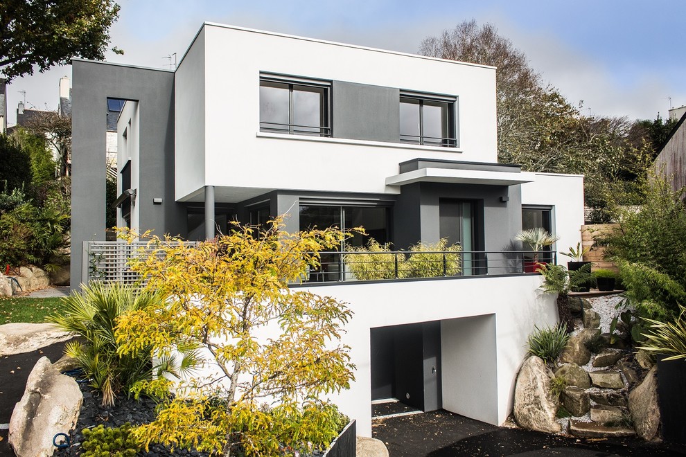 Aménagement d'une grande façade de maison blanche moderne en béton à deux étages et plus avec un toit plat.