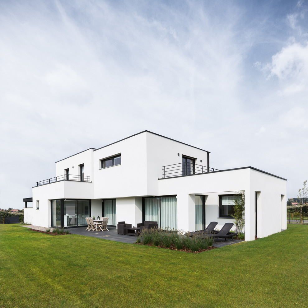 Пример оригинального дизайна: двухэтажный, белый дом среднего размера в современном стиле с плоской крышей