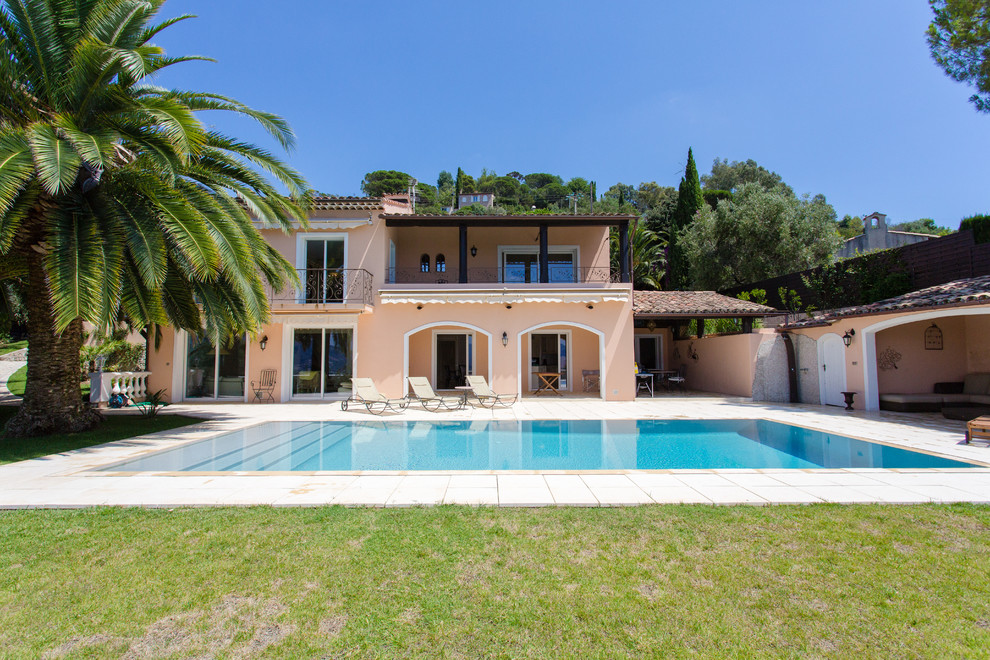 Idée de décoration pour une grande façade de petite villa beige méditerranéenne à un étage avec un toit à deux pans.