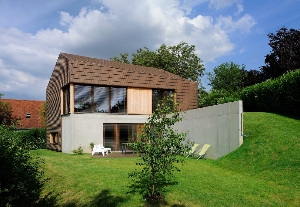Esempio della facciata di una casa marrone contemporanea a due piani con rivestimento in legno e tetto a capanna