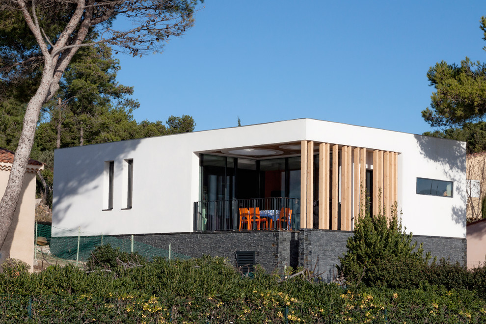 This is an example of a medium sized and white contemporary bungalow house exterior in Marseille with mixed cladding and a flat roof.