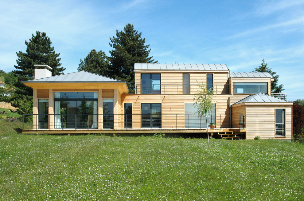Design ideas for a beige and large contemporary split-level detached house in Lyon with wood cladding and a hip roof.