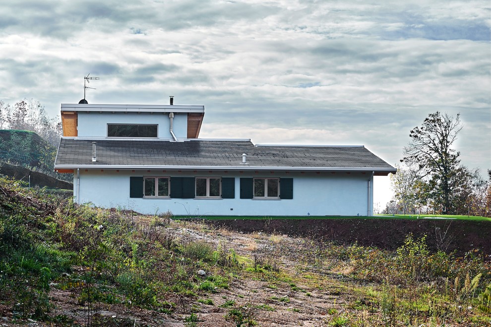 Modelo de fachada de casa blanca actual de tamaño medio de dos plantas con tejado de un solo tendido y tejado de teja de barro
