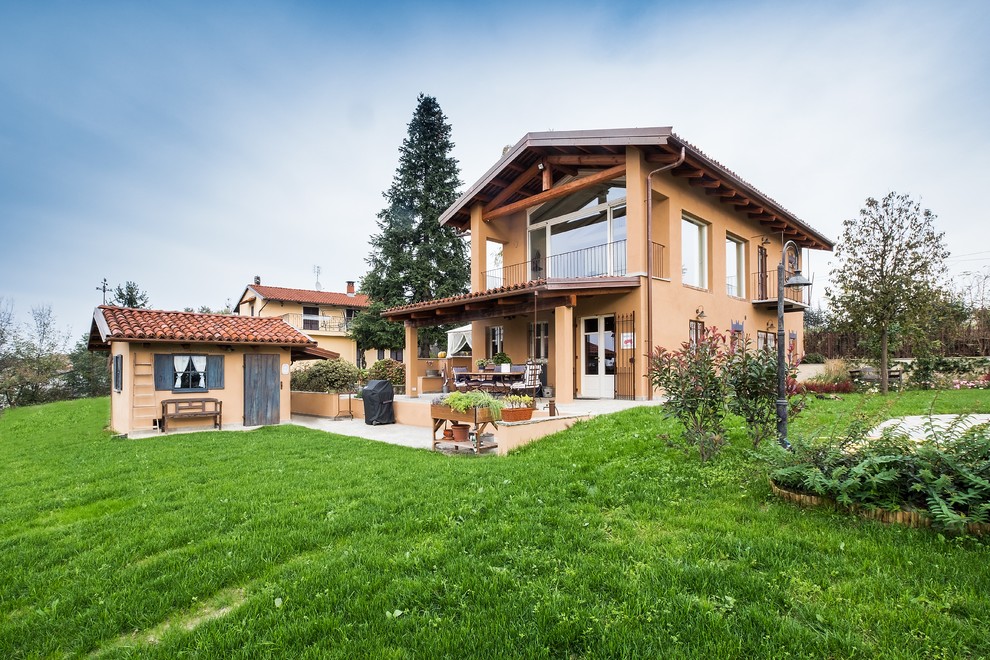 Modelo de fachada beige de estilo de casa de campo grande de dos plantas con revestimiento de estuco y tejado a dos aguas