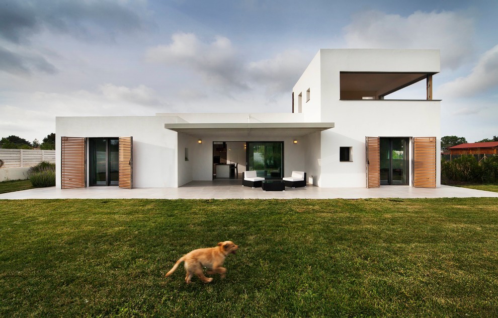 Modelo de fachada de casa blanca minimalista de dos plantas con revestimiento de estuco y tejado plano