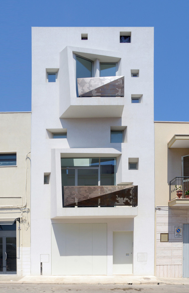 На фото: трехэтажный, белый дом в средиземноморском стиле с плоской крышей