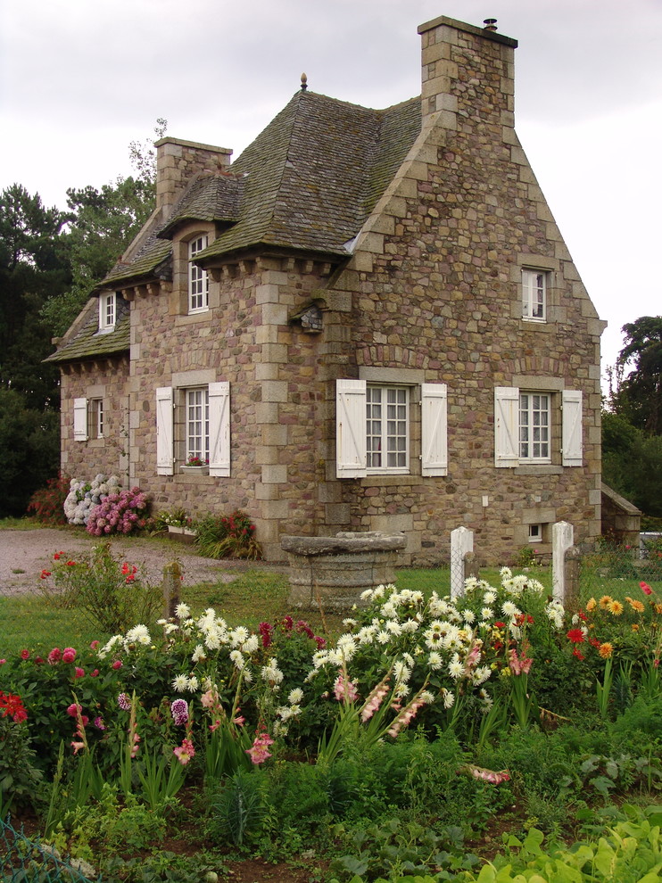 Cette image montre une façade de maison traditionnelle en pierre à un étage et de taille moyenne avec un toit à quatre pans.