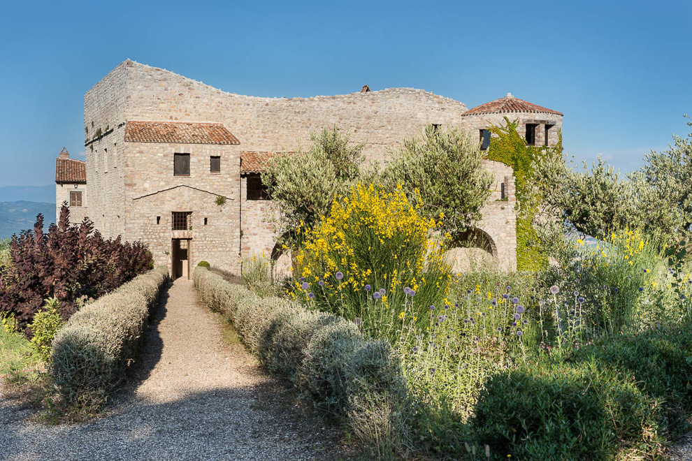 Modelo de fachada beige mediterránea grande de tres plantas con revestimiento de piedra