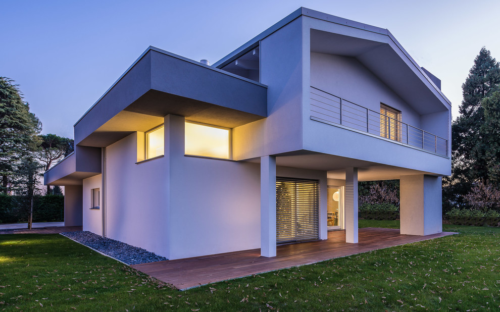 Photo of a white and large contemporary two floor house exterior in Other with wood cladding and a pitched roof.