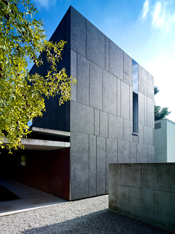 Idee per la facciata di una casa nera contemporanea a tre piani con rivestimento in pietra