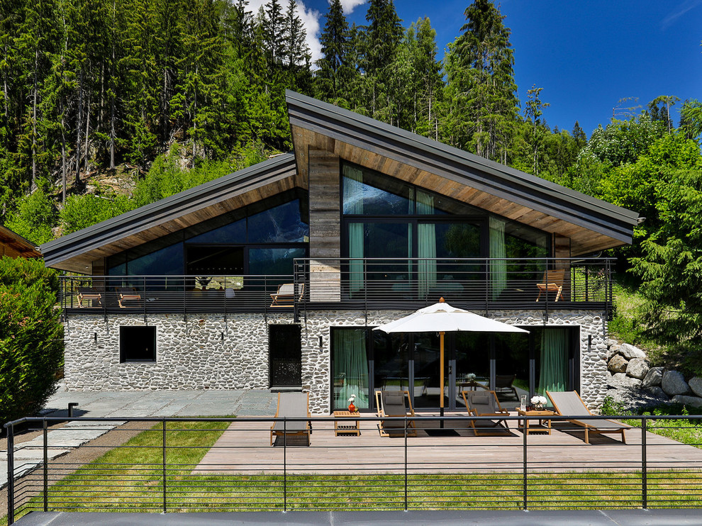 Стильный дизайн: двухэтажный частный загородный дом в стиле рустика с облицовкой из камня и односкатной крышей - последний тренд