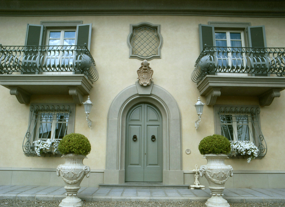 Réalisation d'une grande façade de maison beige tradition en béton à un étage.