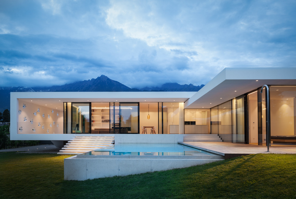 Modelo de fachada de casa blanca minimalista de una planta con tejado plano y revestimiento de vidrio