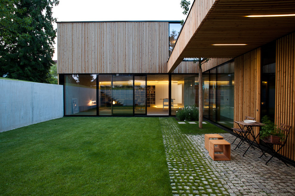 Cette photo montre une grande façade de maison marron tendance en bois à un étage avec un toit plat.