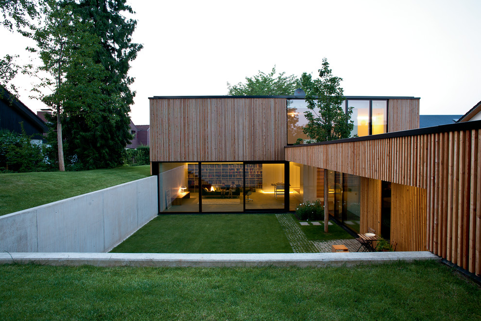 Esempio della facciata di una casa grande marrone contemporanea a due piani con rivestimento in legno e tetto piano