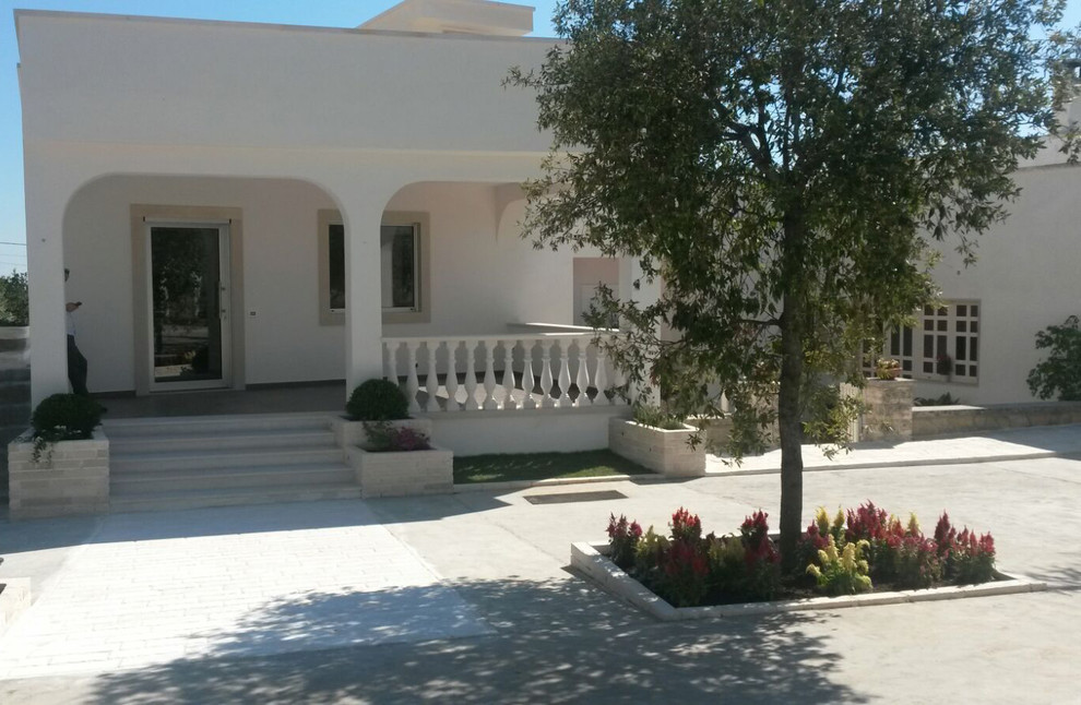Ejemplo de fachada blanca mediterránea de tamaño medio de una planta con revestimientos combinados y tejado plano
