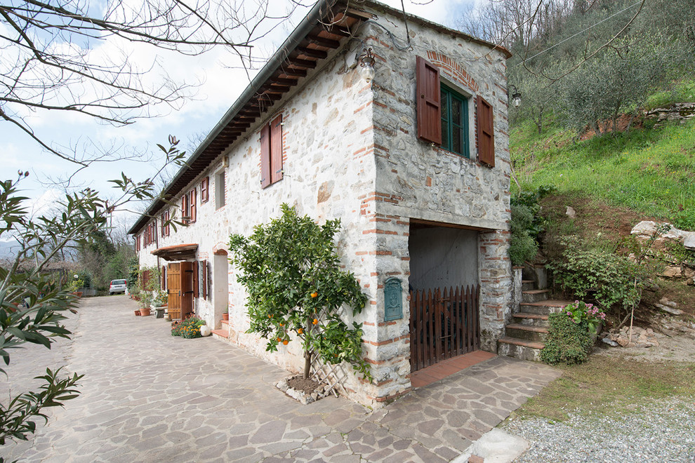 This is an example of a white and medium sized farmhouse two floor house exterior in Florence with stone cladding and a lean-to roof.