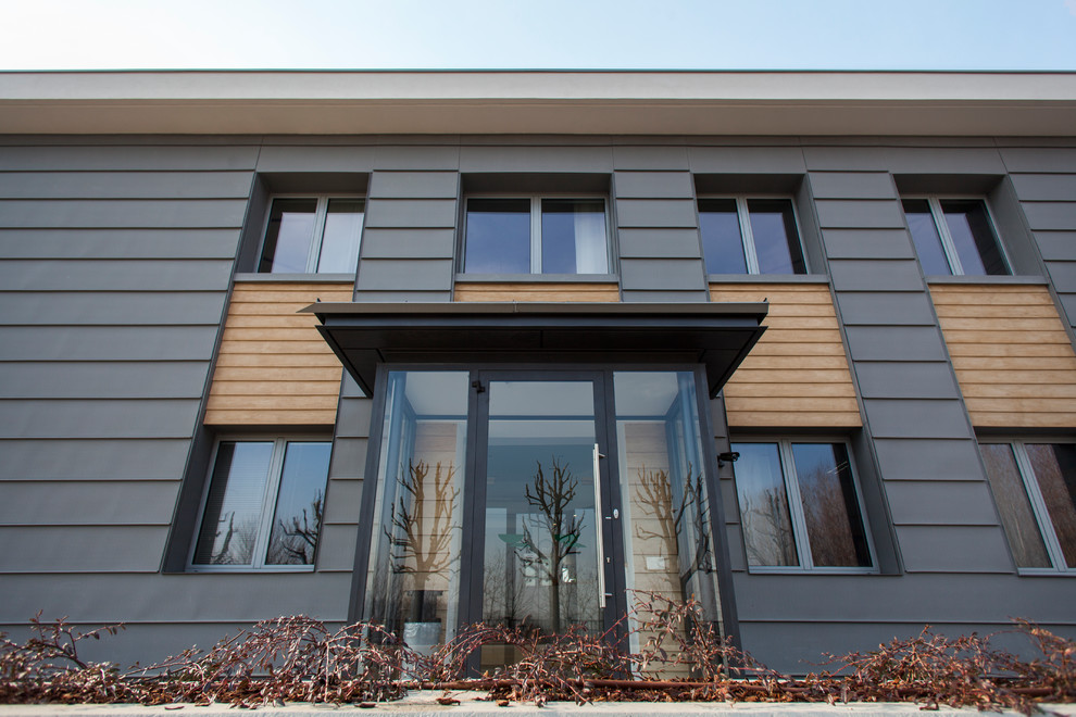 Foto de fachada gris contemporánea grande de dos plantas con revestimiento de metal y tejado a dos aguas
