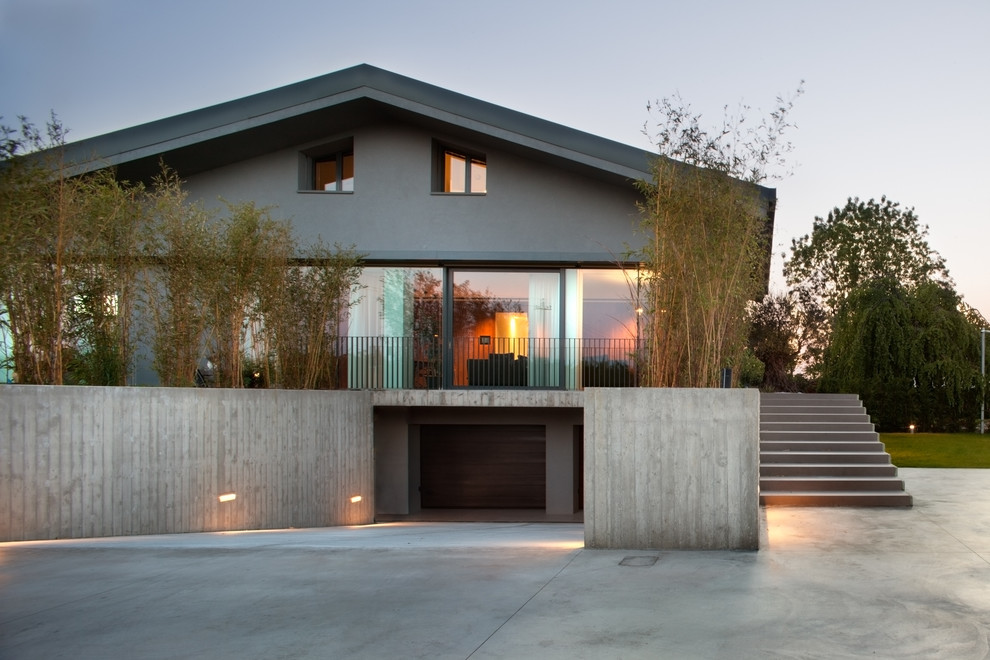 Diseño de fachada gris actual grande de dos plantas con revestimiento de hormigón y tejado a dos aguas