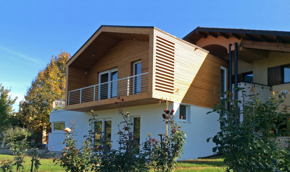 Ejemplo de fachada de casa blanca contemporánea grande de dos plantas con revestimiento de madera y tejado a doble faldón