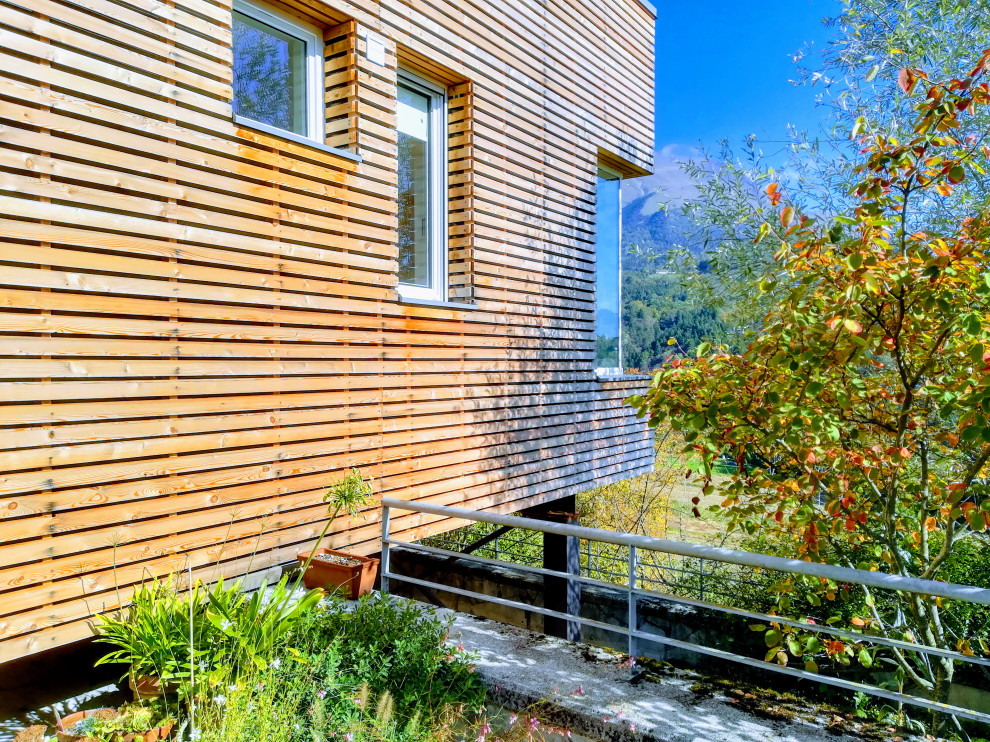 Foto della villa piccola contemporanea a due piani con rivestimento in legno, tetto piano e copertura verde