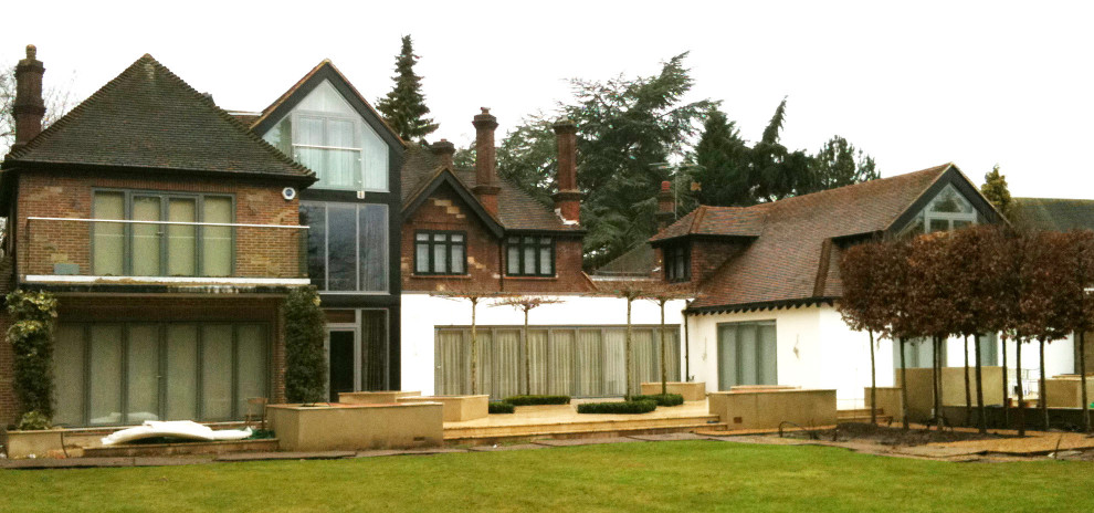 Modelo de fachada de casa multicolor bohemia grande de tres plantas con revestimientos combinados, tejado a cuatro aguas y tejado de teja de barro