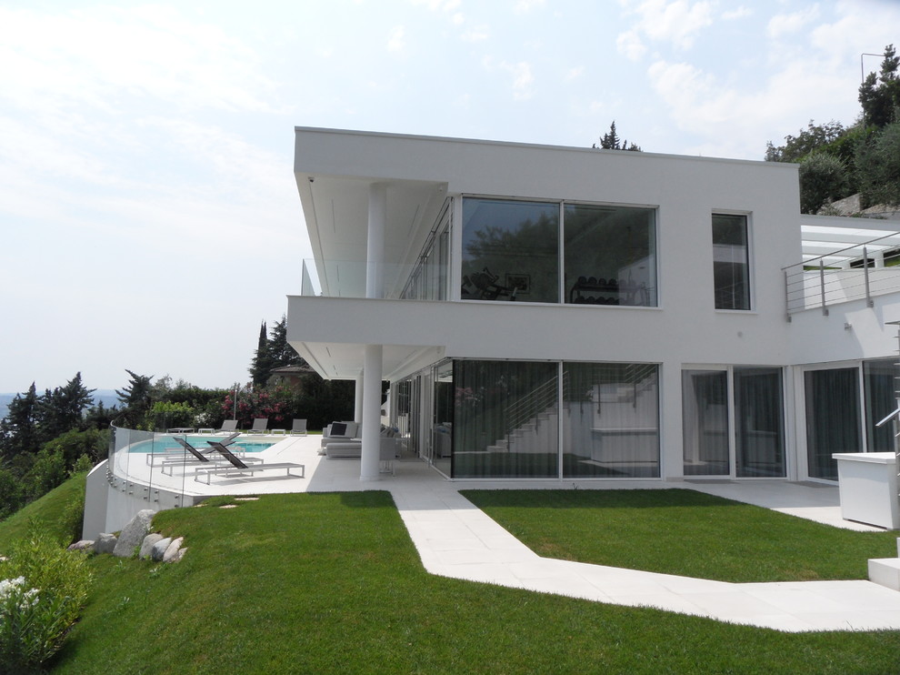 Foto della villa ampia bianca moderna a due piani con rivestimento in stucco e tetto piano