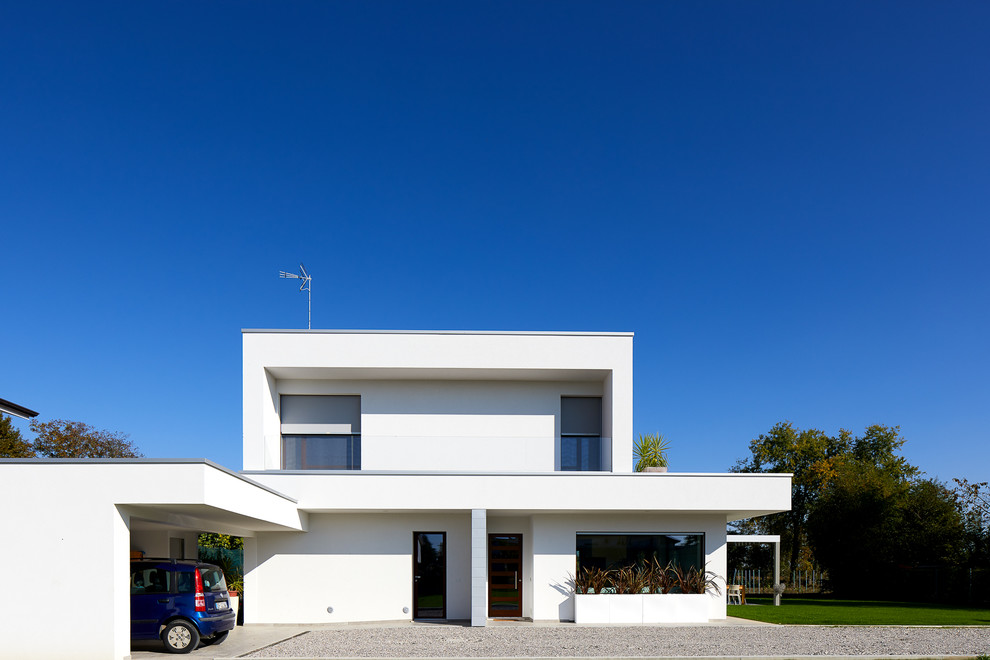 Modelo de fachada de casa blanca actual grande de dos plantas con revestimiento de estuco y tejado plano