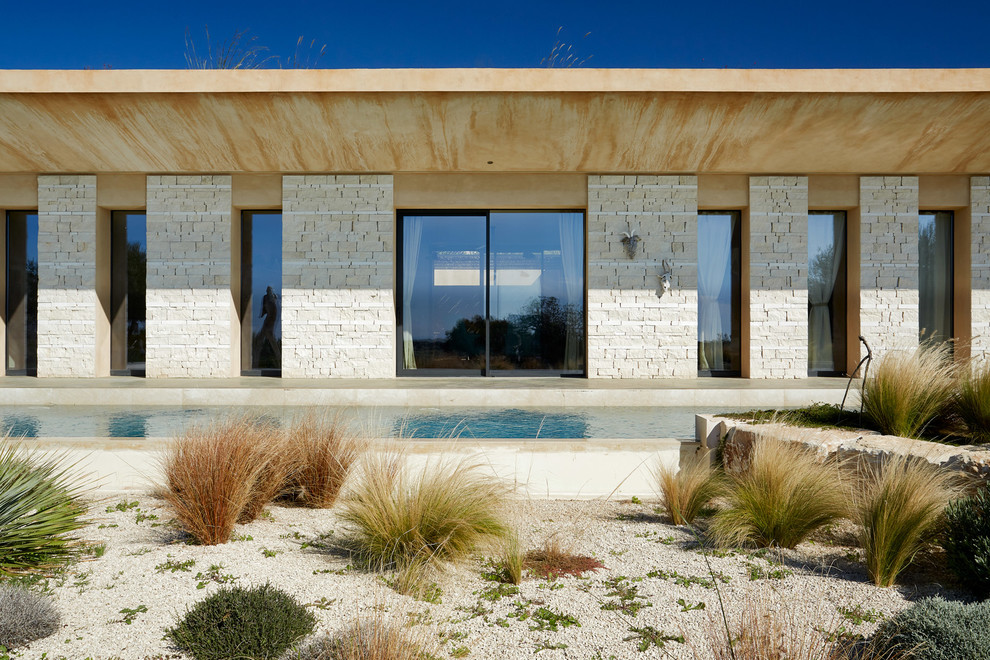 Esempio della villa beige contemporanea a un piano con rivestimento in pietra, tetto piano e copertura verde