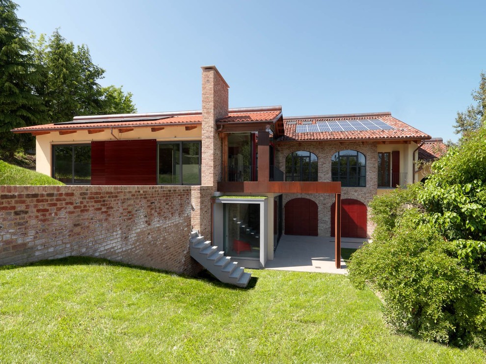 Idée de décoration pour une grande façade de maison marron champêtre en brique à un étage avec un toit à deux pans et un toit en tuile.