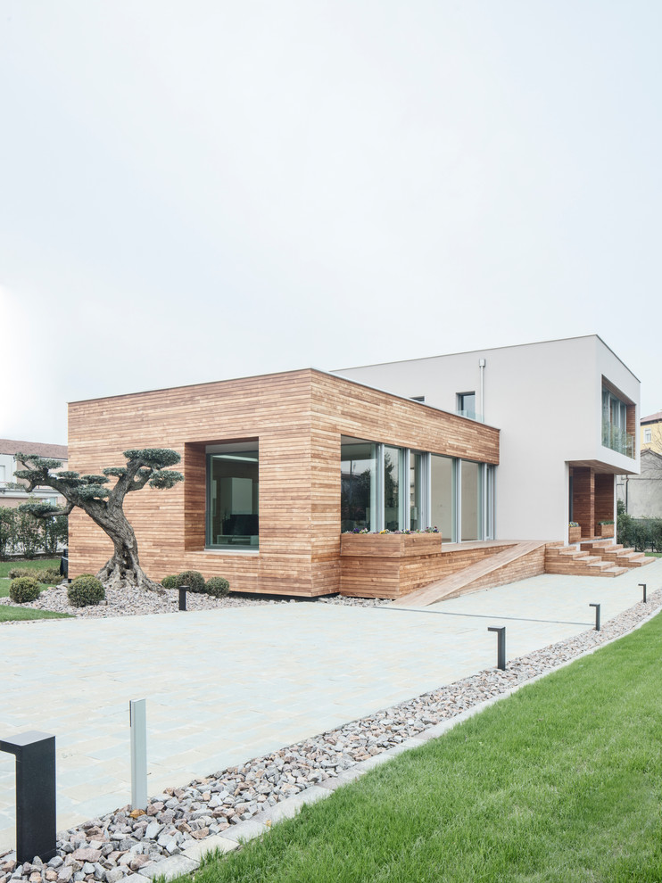 Exemple d'une très grande façade de maison moderne en bois à un étage avec un toit plat et un toit végétal.