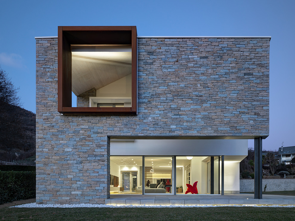 Modelo de fachada de casa gris moderna grande de dos plantas con revestimiento de piedra y tejado plano