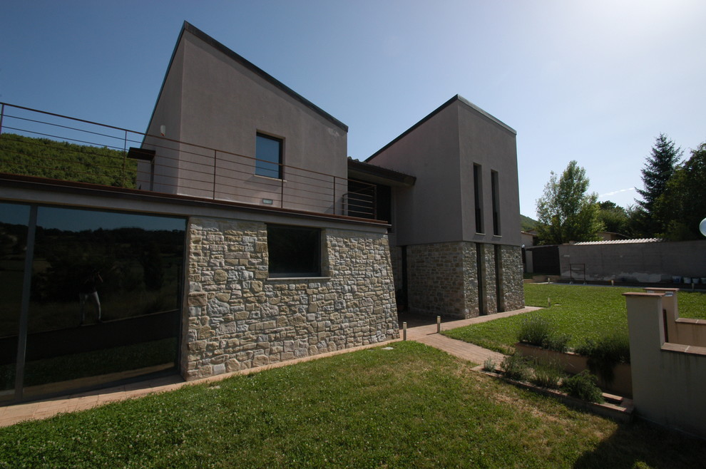 Cette image montre une façade de maison marron design en pierre à un étage et de taille moyenne avec un toit en appentis et un toit en tuile.