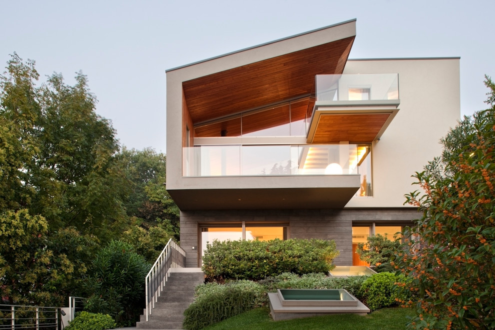 Cette image montre une grande façade de maison beige design à un étage avec un toit en appentis.