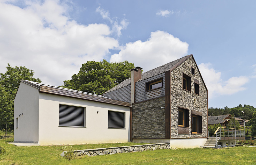 This is an example of a medium sized and brown contemporary two floor house exterior in Turin with mixed cladding and a pitched roof.