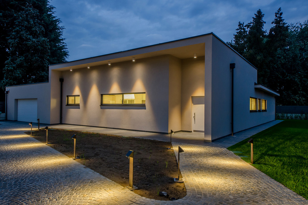 Photo of a large and beige contemporary bungalow render detached house in Milan with a flat roof.