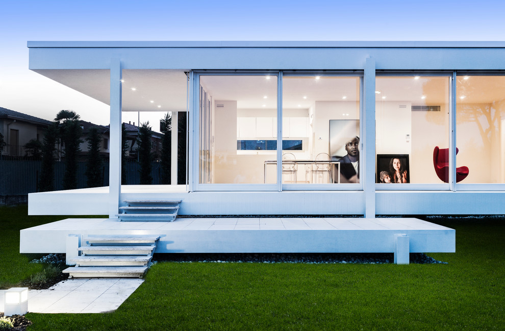Immagine della facciata di una casa bianca contemporanea a un piano con rivestimento in vetro e tetto piano
