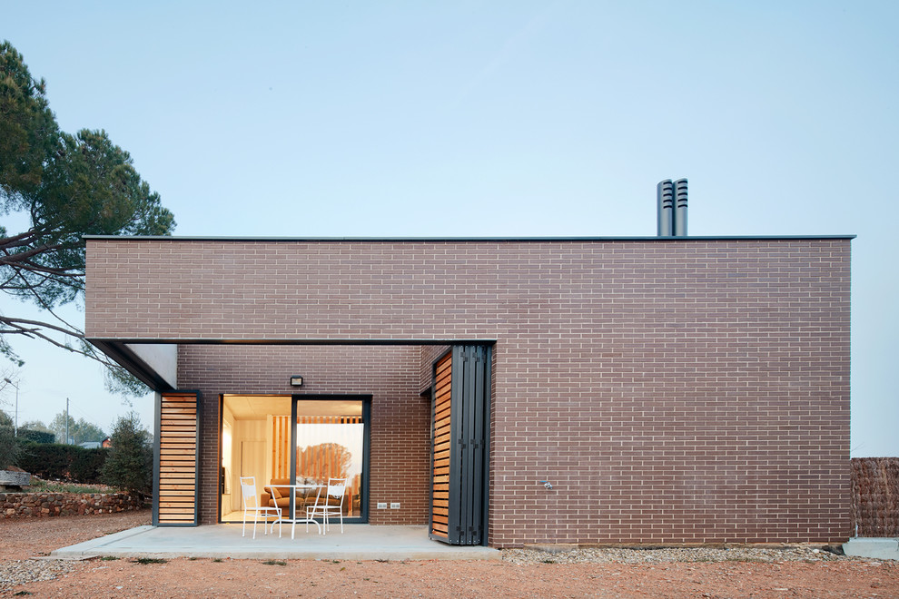 Imagen de fachada beige industrial de tamaño medio de una planta con revestimiento de ladrillo y tejado plano